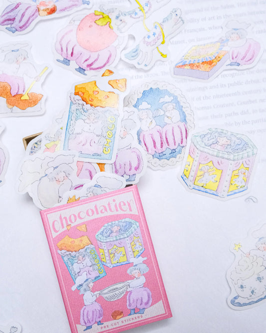 Sticker sheet with pastel-colored desserts and a pink 'Chocolatier' box on a light background, sticker flakes, matchbox, dodolulu, cute, pink, chocolate, nz, hope and letters, new zealand, stationery,