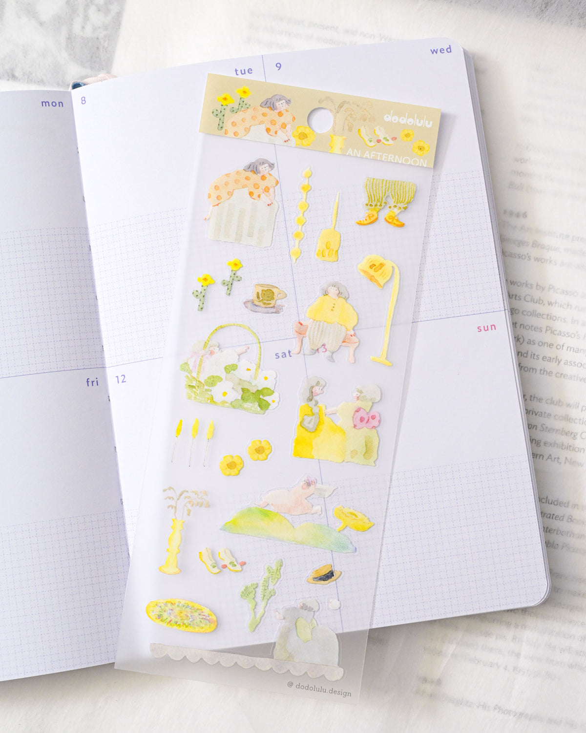 A sheet of cute yellow and pastel planner stickers displayed on an open white grid notebook, with more pages visible in the background. dodolulu, hope and letters, cute, yellow, sticker