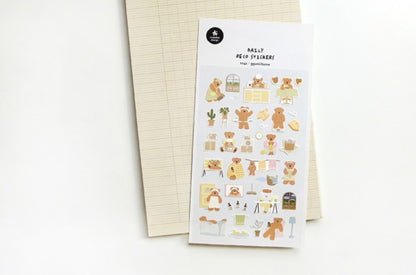 A sheet of cute teddy bear planner stickers labeled 'Ggumi home' lies on top of a beige lined notepad against a clean white background. suatelier, korea, nz, stationery, cute, bear