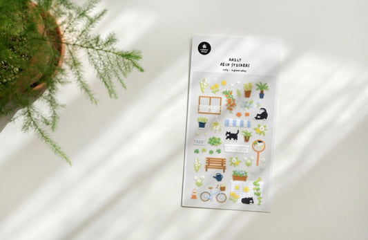 A sheet of cute garden-themed planner stickers displayed on a white surface with soft diagonal shadows, next to a potted green plant. suatelier. nz. cat